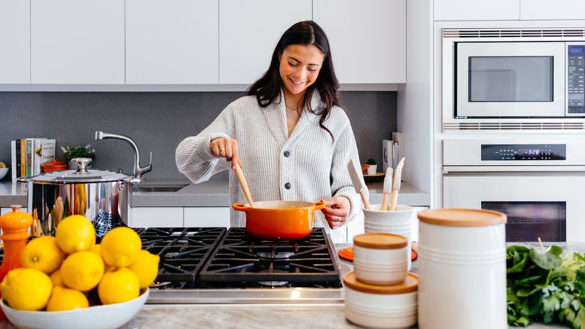 キッチンで鍋をかき混ぜながら料理をする女性